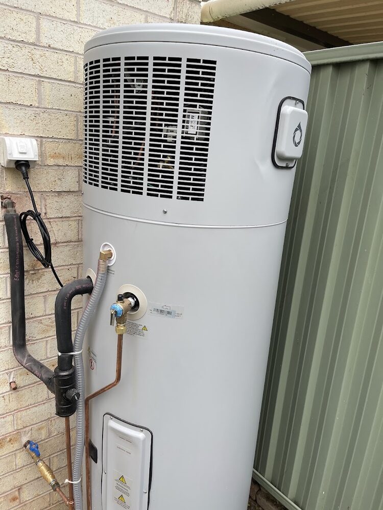 Heat pump hot water unit wired in on a brick wall with its isolator fitted